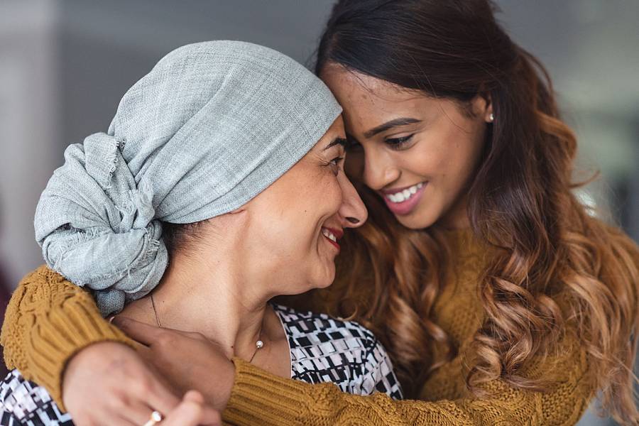 Two smiling women, one of them wearing a turban because of hair loss caused by her cancer treatment