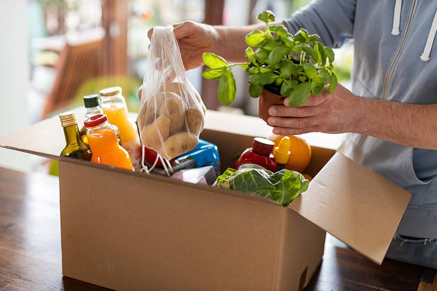 Closeup of man’s hands unpacking a box of healthy groceries