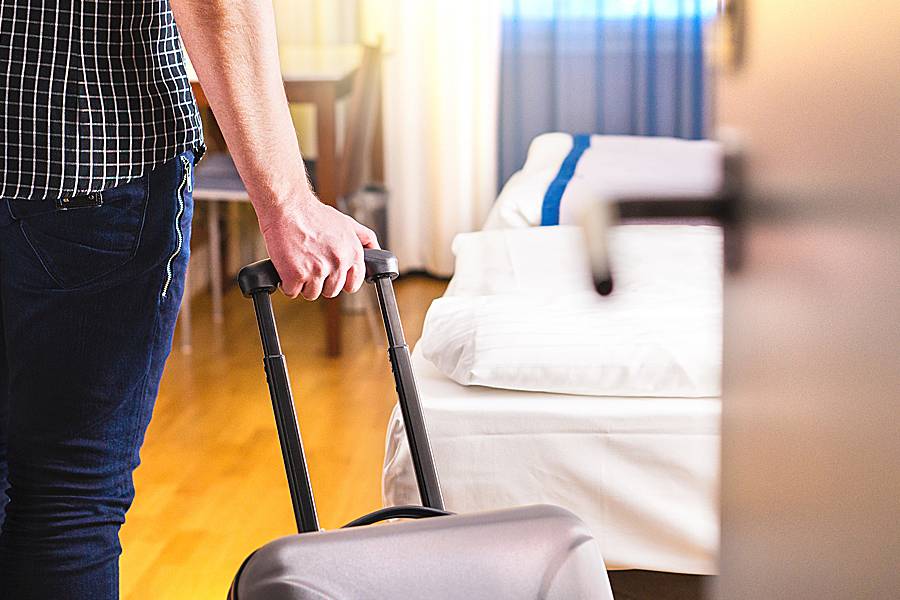 Man pulling suitcase entering a hotel room