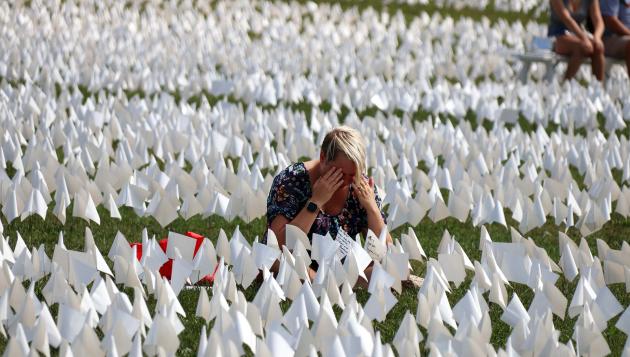 A woman kneels and cries in a field of white flags