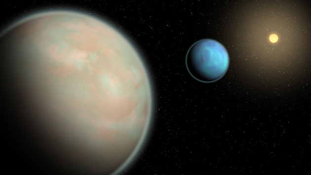 An illustration shows two water-rich exoplanets with heavy layers of haze orbiting their host star in outer space.