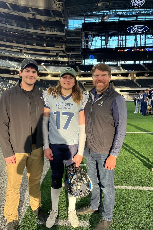 Carter Hogg (center) pictured in a football stadium with brother FJ (left) and dad Jason