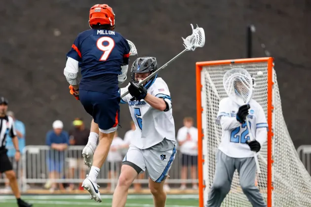 A Virginia lacrosse player in navy blue fires a shot on net