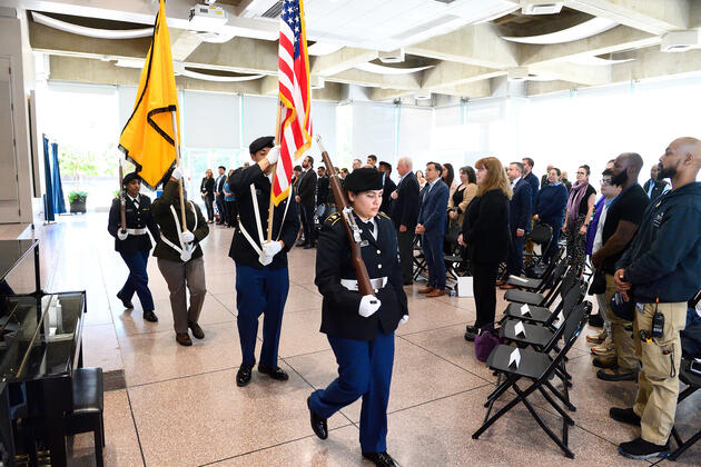 Color guard carries flags while crowd stands