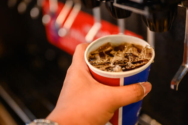 Photo of someone filling up a cup of soda at a soda fountain