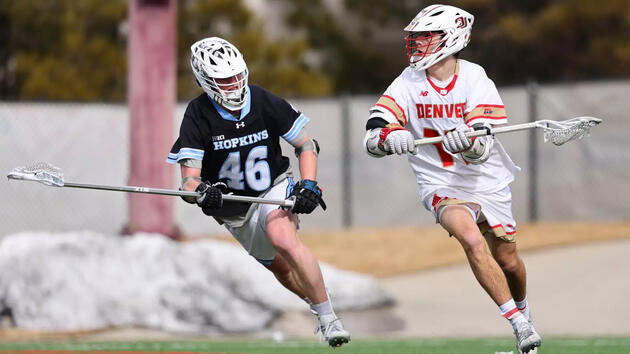 A lacrosse player in white tries to move past a defender in black