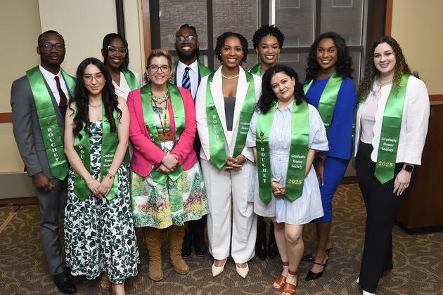 A group of 10 smiles for the camera while wearing green stoles that read "Bouchet Graduate Honor Society 2025."
