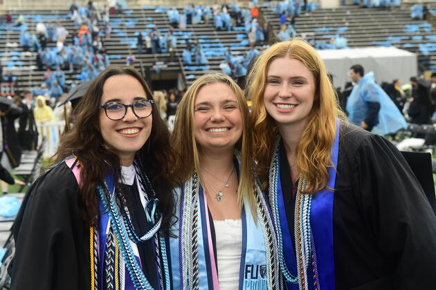 Three graduating college students pose for a photo at JHU Commencement 2025.
