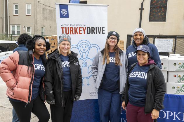 Hopkins volunteers pose by the turkey drive banner