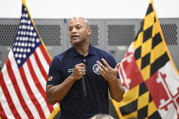 Gov. Wes Moore speaks in front of the American and Maryland flags inside the JHU ROTC building