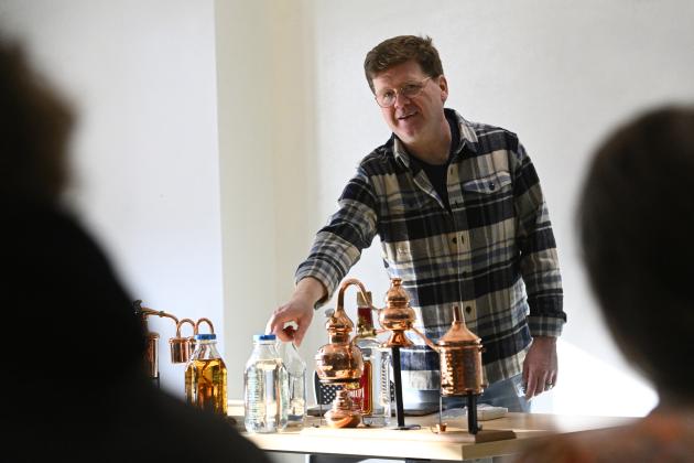 Professor Eric Johnson shows off a table of distilling equipment.