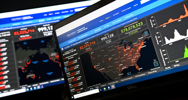 A computer monitor displays the Johns Hopkins Coronavirus Resource Center data tracker