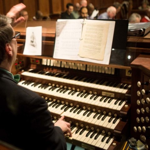 An organist plays on a four-tiered organ